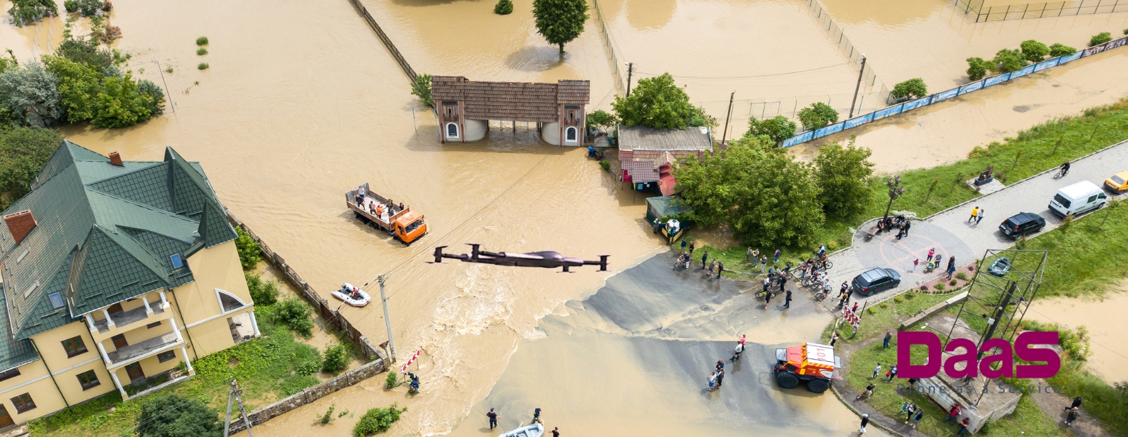 Aerial view of disaster relief operation with a black drone and rescue vehicles on the ground.
